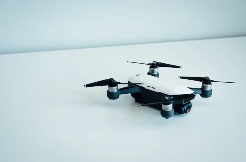 Compact white drone on a minimalistic white surface.