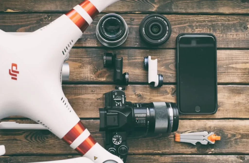 Drone with camera equipment and lenses arranged on a wooden table.