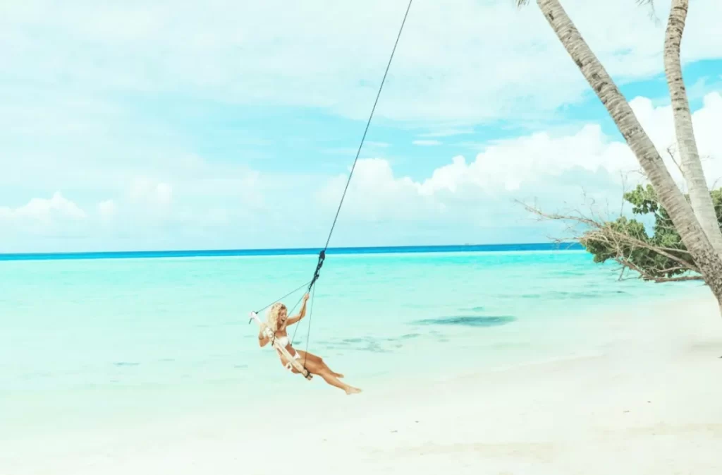 Woman swinging over turquoise waters on Mircari travel blog.